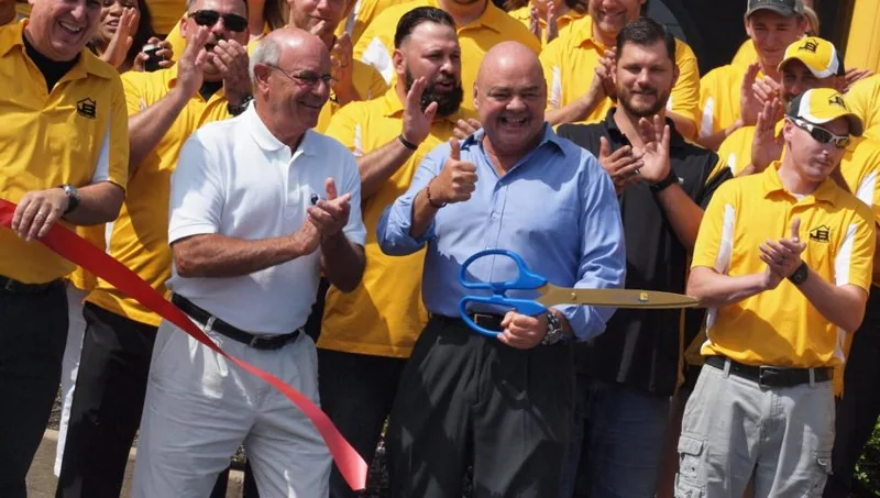 Roofing crew in yellow shirts celebrating together outdoors — John Beal Roofing roofing in Benton, IL
