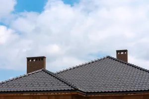 Dark shingled residential roof with multiple brick chimneys — John Beal Roofing roofing in Richland, MO