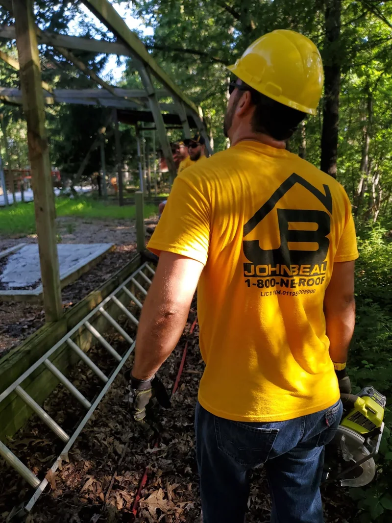 John Beal Roofing crew member in a hard hat on a roof installation covered by the lifetime workmanship warranty