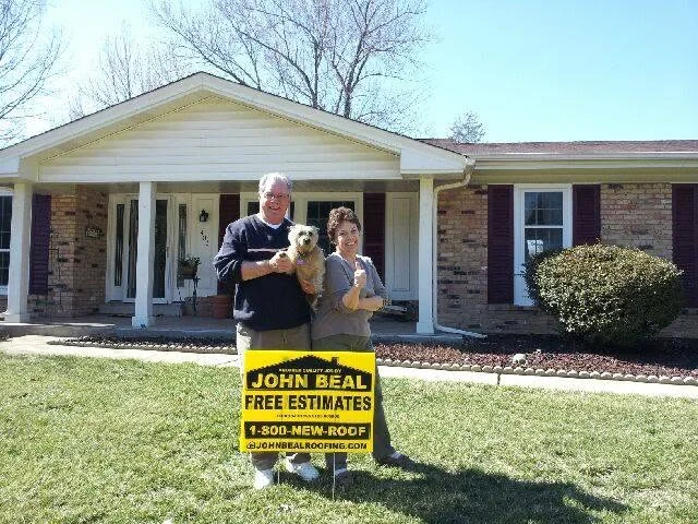 Homeowners and their dog in front of their ranch home with a new roof