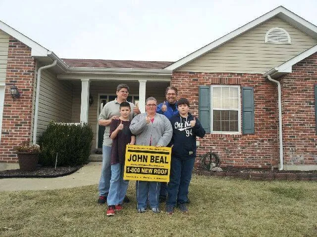Family giving a thumbs up in front of their newly roofed home