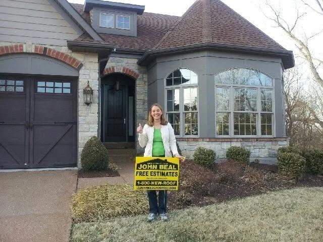 Homeowner with a John Beal yard sign in front of a stone-front home