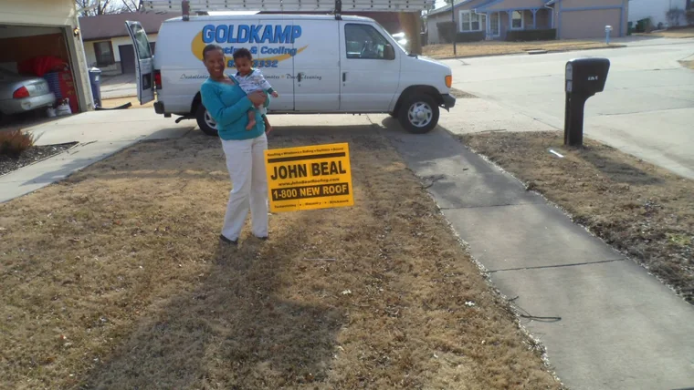 Homeowner holding her child beside a John Beal yard sign in the driveway
