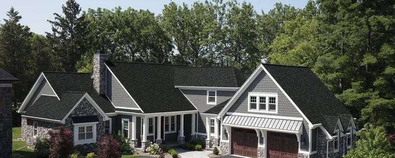 Architectural asphalt shingle roof in onyx black on a stone and shake craftsman home — John Beal Roofing