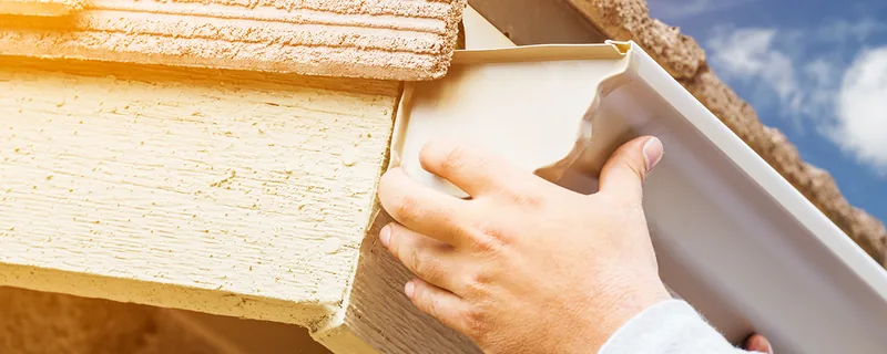 Roofer cutting roofing material with a utility knife — John Beal Roofing