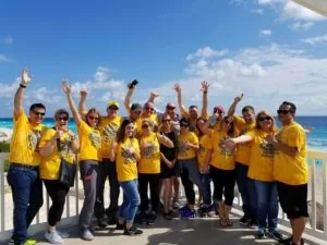 Employees in yellow company shirts cheering outdoors — John Beal Roofing roofing in Greenfield, IN