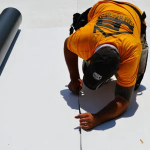 Roofer measuring a flat commercial roofing membrane — John Beal Roofing commercial roofing in Springfield, MO