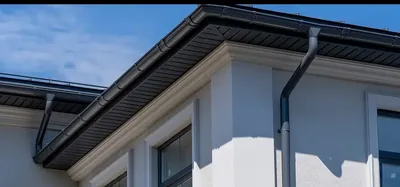 Newly installed metal gutters on a white exterior wall — John Beal Roofing gutter installation in Ballwin, MO