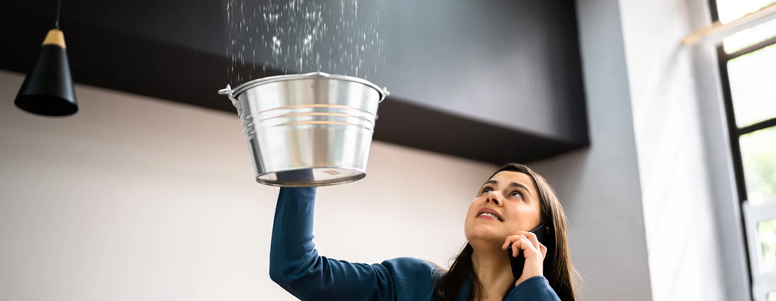 Homeowner catching water in a bucket from a roof leak — John Beal Roofing roofing in Benton, IL