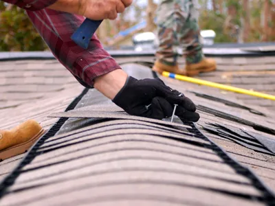 Roofer inspecting and measuring a residential shingle roof — John Beal Roofing gutter installation in Independence, MO