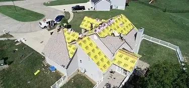 Roofer installing architectural asphalt shingles on a sloped roof — John Beal Roofing roofing in Columbia, MO