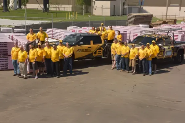 Roofing crew in yellow shirts posing with company trucks — John Beal Roofing roofing in North Kansas City, MO