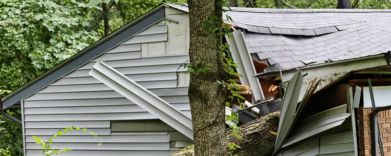 Damaged roof showing exposed wooden rafters and decking — John Beal Roofing storm damage restoration in Fulton, MO