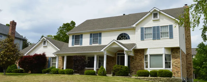 Two-story home with grey siding and a manicured lawn — John Beal Roofing roofing in Versailles, MO