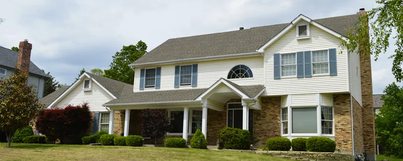 Two-story suburban house with a well-maintained lawn — John Beal Roofing gutter installation in Clever, MO