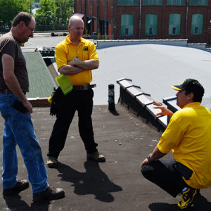 Two commercial roofing contractors talking with the building owner about his roof.