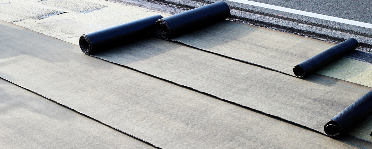 Rolls of EPDM roofing laid out on a commercial roof.