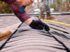 Handing installing shingles on a roof.